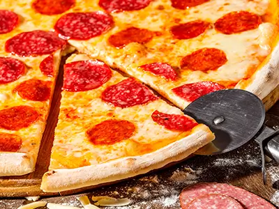 Pepperoni pizza being sliced with a pizza cutter at Horseshoe Lounge & Restaurant, Collinsville, IL